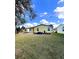 Exterior view of the backyard with a yellow home and green grass on a sunny day at 224 Westwood Dr, Leesburg, FL 34748