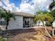 Backyard featuring a screened lanai, landscaping, and mulch beds, all shaded by mature palm trees at 2367 Camden Ter, The Villages, FL 32162