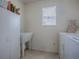 Functional laundry room with a utility sink, storage cabinet, and bright natural light from window at 2367 Camden Ter, The Villages, FL 32162