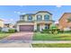 Charming two-story home featuring a brick-paved driveway, manicured lawn, and an inviting front porch at 2727 Retriever Dr, Clermont, FL 34711