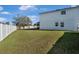 Large grassy backyard with a white fence, mature tree, and plenty of space for outdoor activities at 303 Red Kite Dr, Groveland, FL 34736
