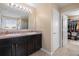 Bathroom featuring double sinks, dark cabinets, granite countertops, and a walk-in closet at 303 Red Kite Dr, Groveland, FL 34736