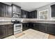 This kitchen has stainless steel appliances, tile floors, and black cabinets at 303 Red Kite Dr, Groveland, FL 34736