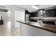 This kitchen has an island with granite countertops, tile floors, and black cabinets at 303 Red Kite Dr, Groveland, FL 34736