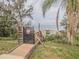 Lakeside access with a wooden boardwalk and gated entrance leading to a tranquil dock and boat lift at 3339 Landing Vw, Tavares, FL 32778