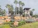 Elaborate water feature with cascading waterfalls, decorative rock formations, and lush landscaping with palm trees at 3339 Landing Vw, Tavares, FL 32778