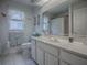 Well-lit bathroom with vanity, mirror reflecting the shower, toilet, and decorative flamingo accents at 33409 Pennbrooke Pkwy, Leesburg, FL 34748
