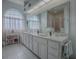 Bright bathroom with double vanity, arched window and large mirror reflecting a glass-enclosed shower at 33409 Pennbrooke Pkwy, Leesburg, FL 34748