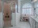 Bright bathroom featuring a glass-enclosed shower, arched window with privacy curtains, and white shelving at 33409 Pennbrooke Pkwy, Leesburg, FL 34748