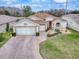 Well-kept single-story home featuring lush landscaping and a brick driveway at 33409 Pennbrooke Pkwy, Leesburg, FL 34748