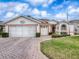 Front view of a charming single-story home with a brick driveway and well-kept lawn at 33409 Pennbrooke Pkwy, Leesburg, FL 34748