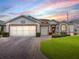 Charming home exterior showcasing a brick driveway, lush lawn, and an attached two-car garage at 33409 Pennbrooke Pkwy, Leesburg, FL 34748