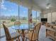 Bright sunroom with glass table, four chairs, and a view of the backyard at 33409 Pennbrooke Pkwy, Leesburg, FL 34748