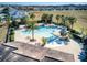 Aerial view of pool and tile roof, with a neighborhood in the background, surrounded by lush palm trees at 412 Arbor Pointe Ave, Minneola, FL 34715