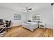 Bright bedroom with hardwood floors, two windows, a ceiling fan, and simple furniture at 4723 Cr 306, Lake Panasoffkee, FL 33538