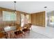The dining room area features wood paneled walls, neutral colors and a sliding glass door to the patio at 4918 County Road 114, Wildwood, FL 34785