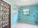 Bright laundry room with blue brick walls, wire shelving, and a door with a shoe organizer at 4918 County Road 114, Wildwood, FL 34785