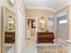 Inviting hallway leads to the bathroom, featuring elegant tile floors, decorative mirrors, and classic wood dressers at 6025 Dijulio Ter, The Villages, FL 32163