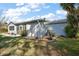 Light blue home featuring a garage, well-kept lawn, and diverse landscaping at 705 Cortez Ave, The Villages, FL 32159