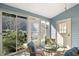Charming sunroom with a glass table, blue cushions, and sliding glass doors to the lush outdoors at 705 Cortez Ave, The Villages, FL 32159