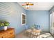 Bright sunroom with blue walls, tile floor, and a ceiling fan with glass table and chairs at 705 Cortez Ave, The Villages, FL 32159