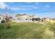 Spacious backyard with well-maintained lawn, screened porch, and view of neighboring houses under a sunny sky at 736 Heathrow Ave, The Villages, FL 32159