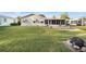 Large grassy backyard features a screened porch, and a stone fire pit for outdoor entertaining at 736 Heathrow Ave, The Villages, FL 32159