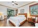 Bright main bedroom featuring a wooden bed frame, ceiling fan, and a view of the outside at 8888 Beacon Hill Ave, Mount Dora, FL 32757