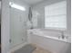 Bright bathroom features a tiled floor, soaking tub with chrome fixtures, and clear glass shower enclosure at 9052 Se 130Th Loop, Summerfield, FL 34491