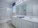 Bright bathroom with a large mirror, dual sinks, and a shower-tub combo with glass doors at 9052 Se 130Th Loop, Summerfield, FL 34491
