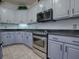 Well-equipped kitchen with gray cabinets, stainless steel appliances, and granite countertops at 9052 Se 130Th Loop, Summerfield, FL 34491