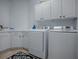 Well-lit laundry room with white cabinets, countertops, and modern washer and dryer units at 9052 Se 130Th Loop, Summerfield, FL 34491