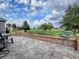 Outdoor patio with stone pavers and brick accents, overlooking a lush green space and serene landscaping at 9052 Se 130Th Loop, Summerfield, FL 34491