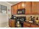 A functional kitchen with wood cabinetry, granite countertops, and black appliances at 907 Charo Pkwy # 915, Davenport, FL 33897