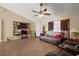 A cozy living room featuring tile flooring, a ceiling fan, shelving, furniture, and ample natural light at 909 Palm Forest Ln, Minneola, FL 34715