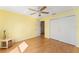 A bright bedroom featuring yellow walls, fan, wood floors, closet, and a door to the hallway at 9312 Se 172Nd Wayside Pl, The Villages, FL 32162