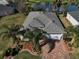 Landscaped home with a brick driveway, lush yard, and a serene view of the adjacent pond at 10173 Julia Isles Ave, Oxford, FL 34484