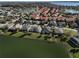 Community with many single-story homes, some with terracotta roofs, surrounding a tranquil pond at 10173 Julia Isles Ave, Oxford, FL 34484