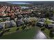 Overhead view of a residential area with houses near a lake, showcasing red tile roofs and lush landscaping at 10173 Julia Isles Ave, Oxford, FL 34484