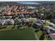 Birds eye view of lakeside homes with red-tiled roofs, surrounded by mature trees and picturesque landscaping at 10173 Julia Isles Ave, Oxford, FL 34484