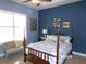 Cozy bedroom featuring a four-poster bed with blue and white bedding, complemented by ample natural light from the window at 10173 Julia Isles Ave, Oxford, FL 34484