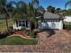 Charming single-story home with a brick driveway, two-car garage, and mature palm trees in the front yard at 10173 Julia Isles Ave, Oxford, FL 34484