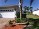 View of a two car garage, landscaping and mulch at 10173 Julia Isles Ave, Oxford, FL 34484