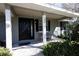 Close-up of the front porch with a dark front door, house number, seating area, and lush green foliage at 10648 Lake Hill Dr, Clermont, FL 34711