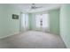 This light green bedroom features two windows with sheer curtains, a ceiling fan and carpeted floors at 1414 Georgetown Ave, The Villages, FL 32162