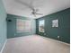 Carpeted bedroom with ceiling fan, two windows with blinds, and a calming green accent wall at 1414 Georgetown Ave, The Villages, FL 32162