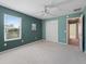 This carpeted bedroom features a ceiling fan, window with blinds, closet, and a calming green accent wall at 1414 Georgetown Ave, The Villages, FL 32162