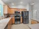 Fully equipped kitchen with modern stainless steel appliances, warm wood cabinets, and tile backsplash at 1414 Georgetown Ave, The Villages, FL 32162