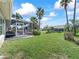 Expansive backyard featuring a screened lanai, lush lawn, and mature tropical landscaping creating a private outdoor retreat at 17504 Se 119Th Cir, Summerfield, FL 34491