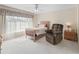 Bright bedroom with a plush recliner chair, soft carpet, and natural light through sheer curtains at 17504 Se 119Th Cir, Summerfield, FL 34491